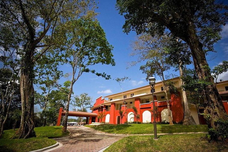 Edificio de la Casa Club de fachada terracota rodeado de árboles de gran tamaño