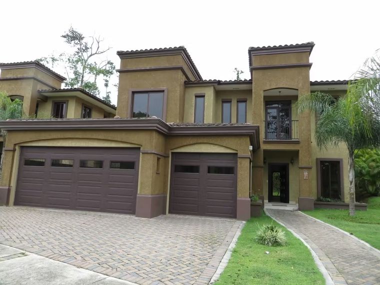 Casa de dos niveles con fachada ocre, doble garaje y entrada de adoquines