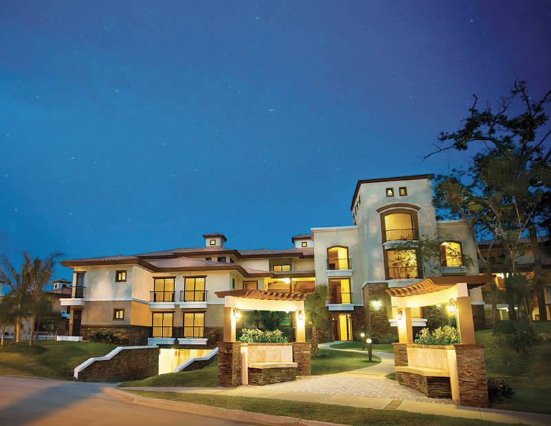 Edificio Garden iluminado al anochecer, con pérgola de acceso y jardineras de piedra