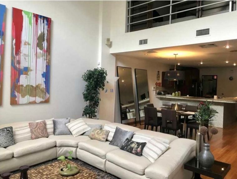 Sala de un Loft con techo de doble altura, mezzanine con baranda y cocina abierta al fondo