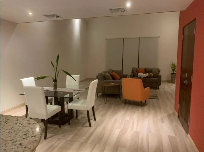 Sala y comedor de un Loft con piso de madera clara y mobiliario contemporáneo
